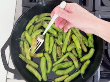 Removing the peppers that are ready first from the skillet.
