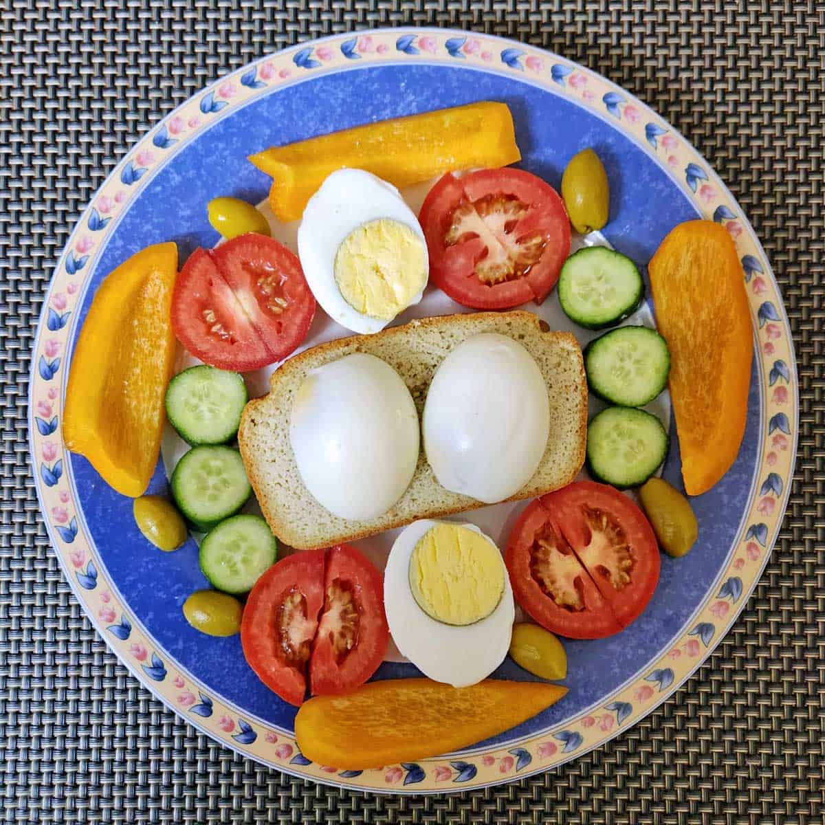 A slice of almond flour bread is served with hard-boiled eggs and veggies.