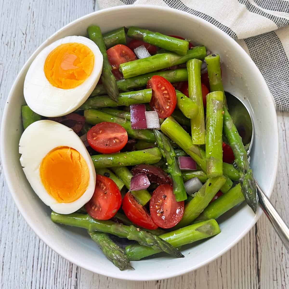 Asparagus salad is topped with eggs.