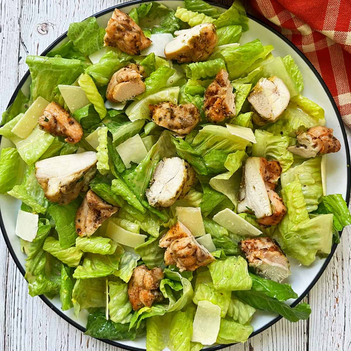 Caesar salad is topped with chicken.