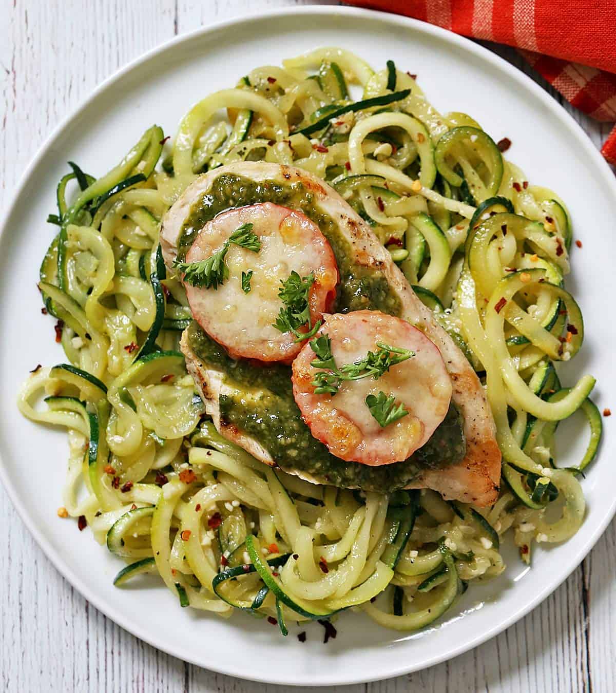 Pesto chicken is served on a bed of zucchini noodles.