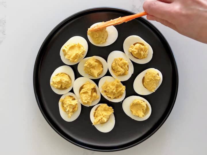 Spooning the creamy yolk nmixture back into the egg whites.