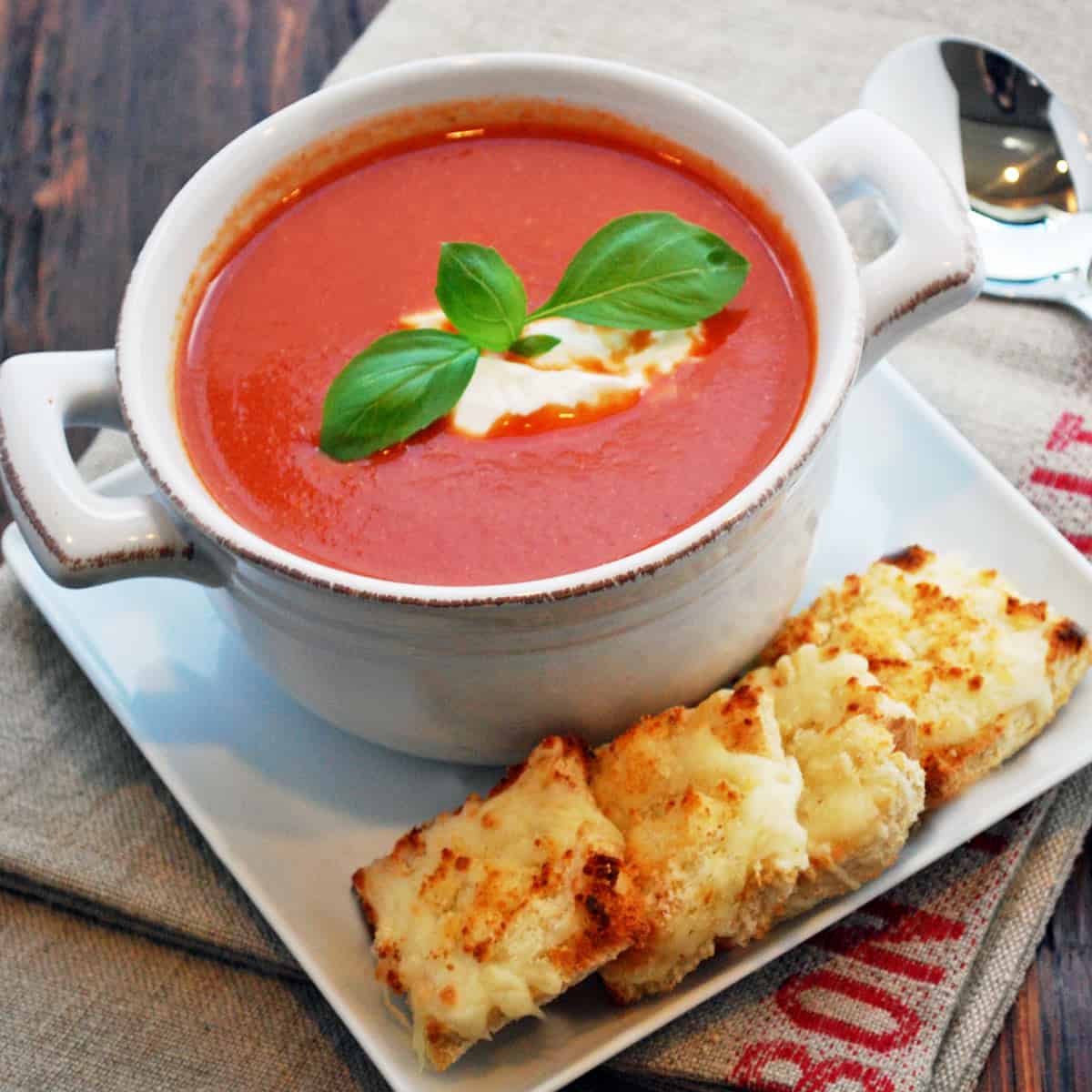 Tomato soup is served with grilled cheese squares.