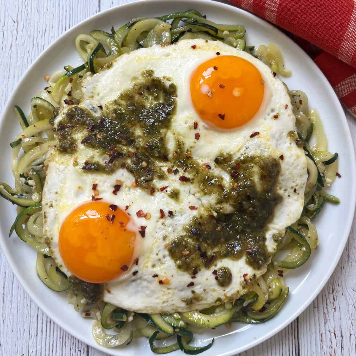 Zucchini noodles are topped with pesto eggs.
