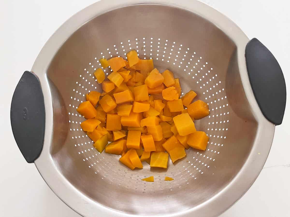 Draining the cooked squash in a colander.