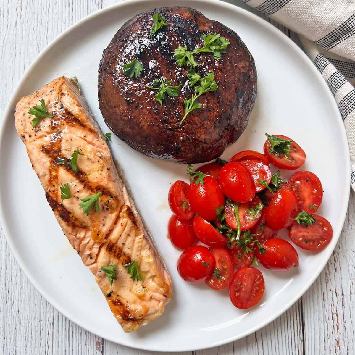 Grilled salmon is served with a grilled portobello mushrooms and tomato salad.