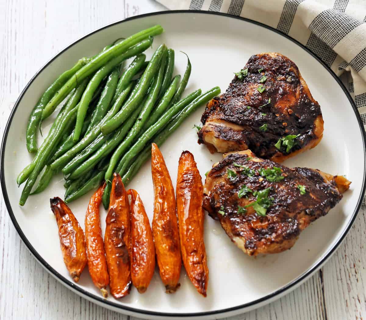 Jerk chicken is served with roasted carrots and green beans.