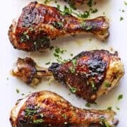 Jerk chicken is served on a white plate, topped with parsley.