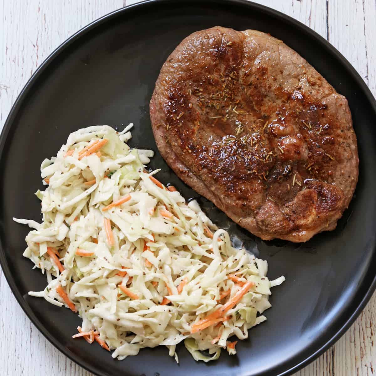 Lamb steak is served with coleslaw.