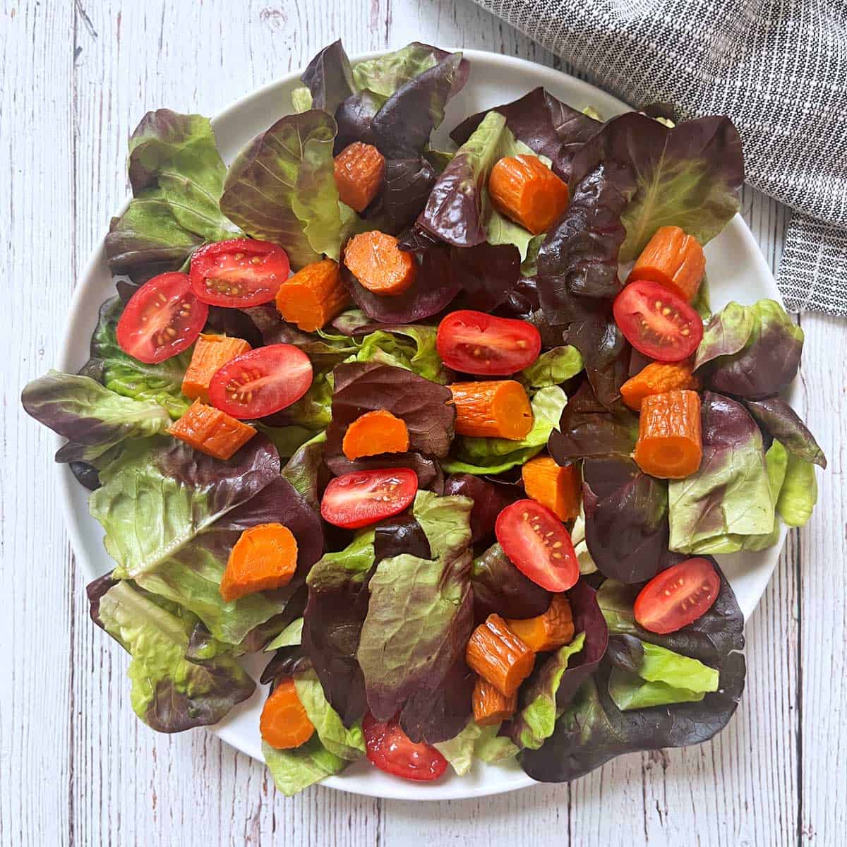Leftovers of roasted carrots were sliced and added to a salad of lettuce and tomatoes.