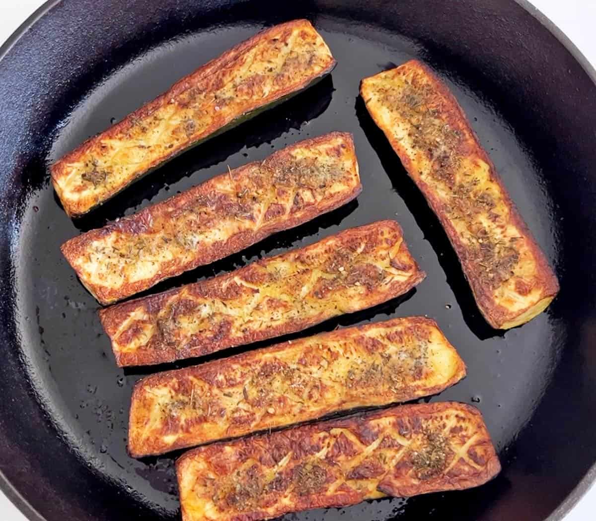 Roasted zucchini is served in a skillet.