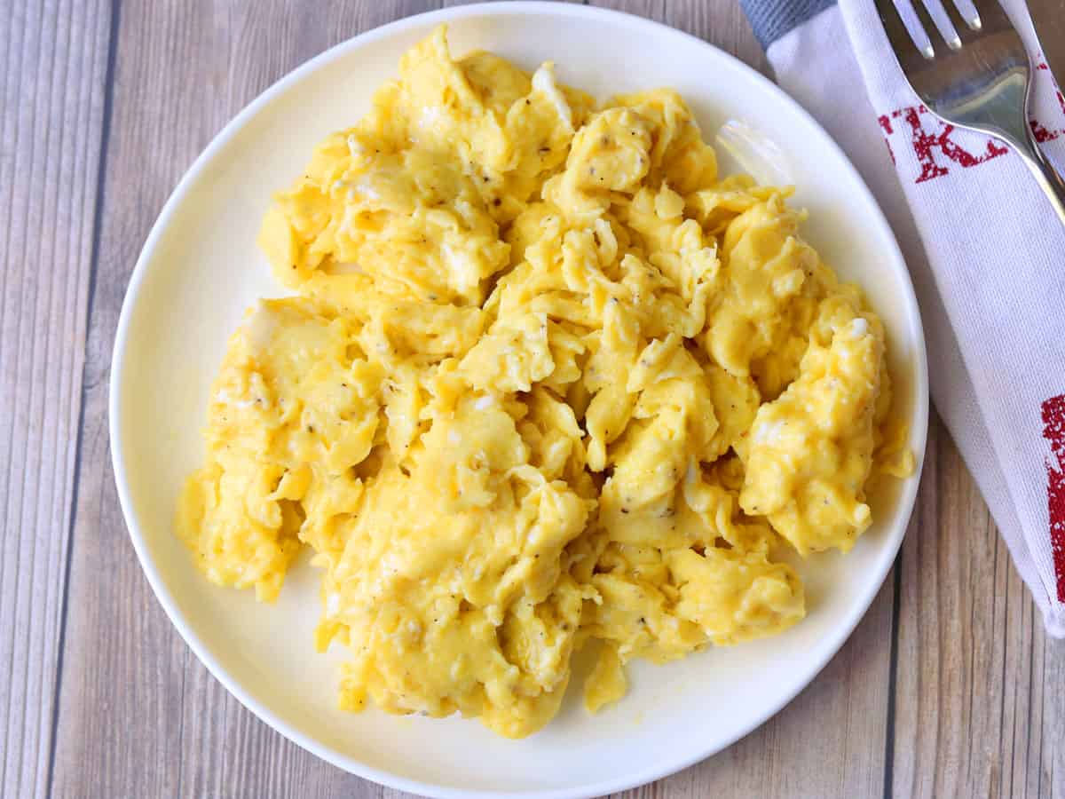 Scrambled eggs are served on a white plate.