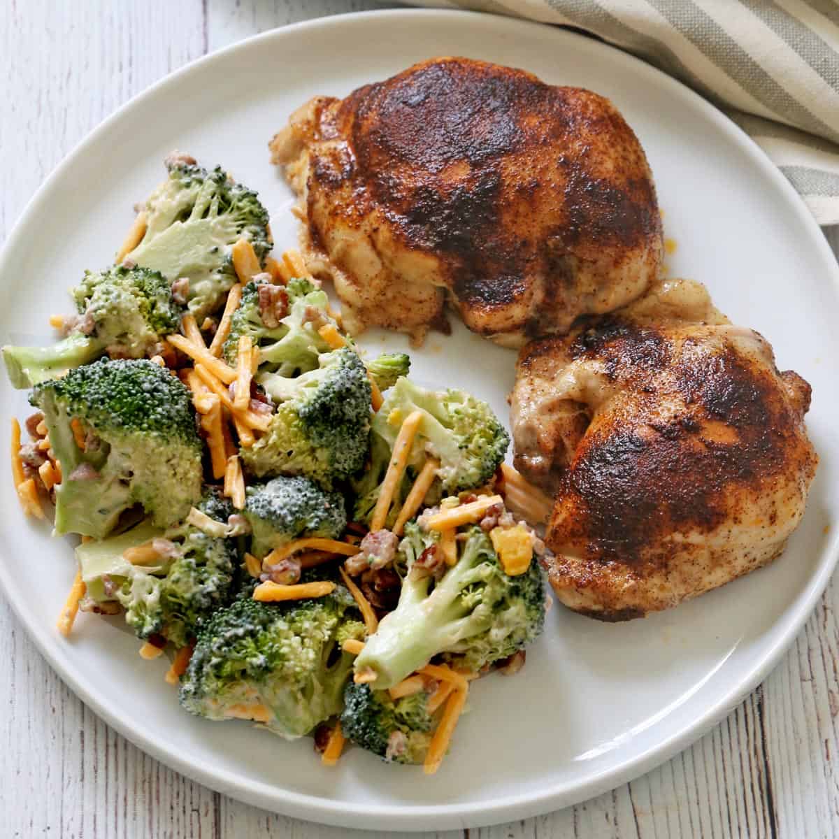 Boneless chicken thighs are served with broccoli salad.