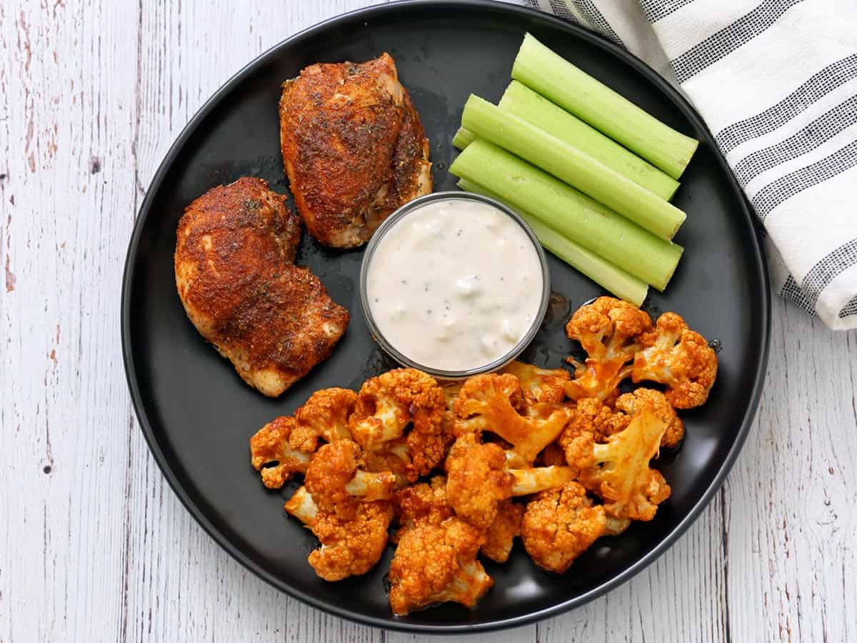 Cajun chicken is served with buffalo cauliflower, celery, and blue cheese dressing.