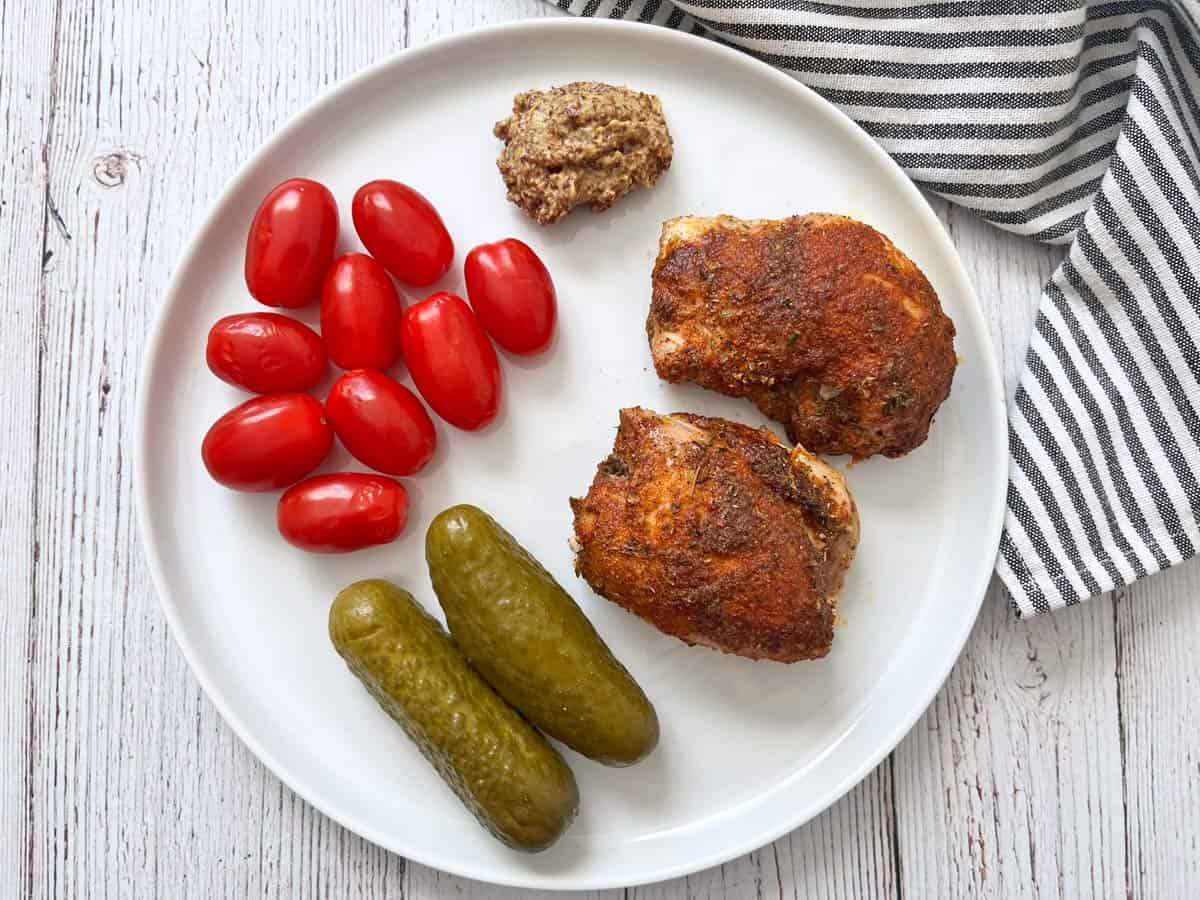 Cajun chicken leftovers are served with tomatoes, cucumber pickles, and mustard.