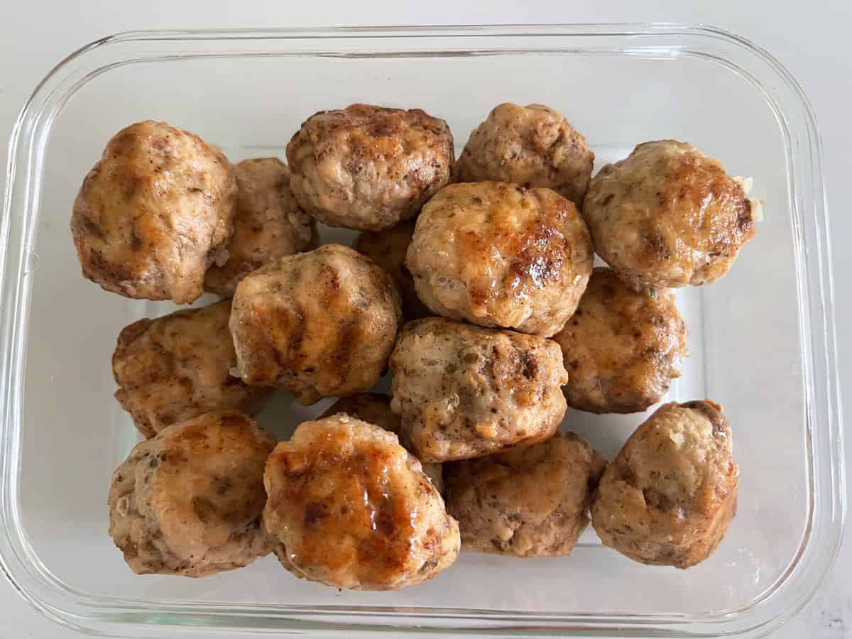 Leftover chicken meatballs are kept in a glass food storage container.