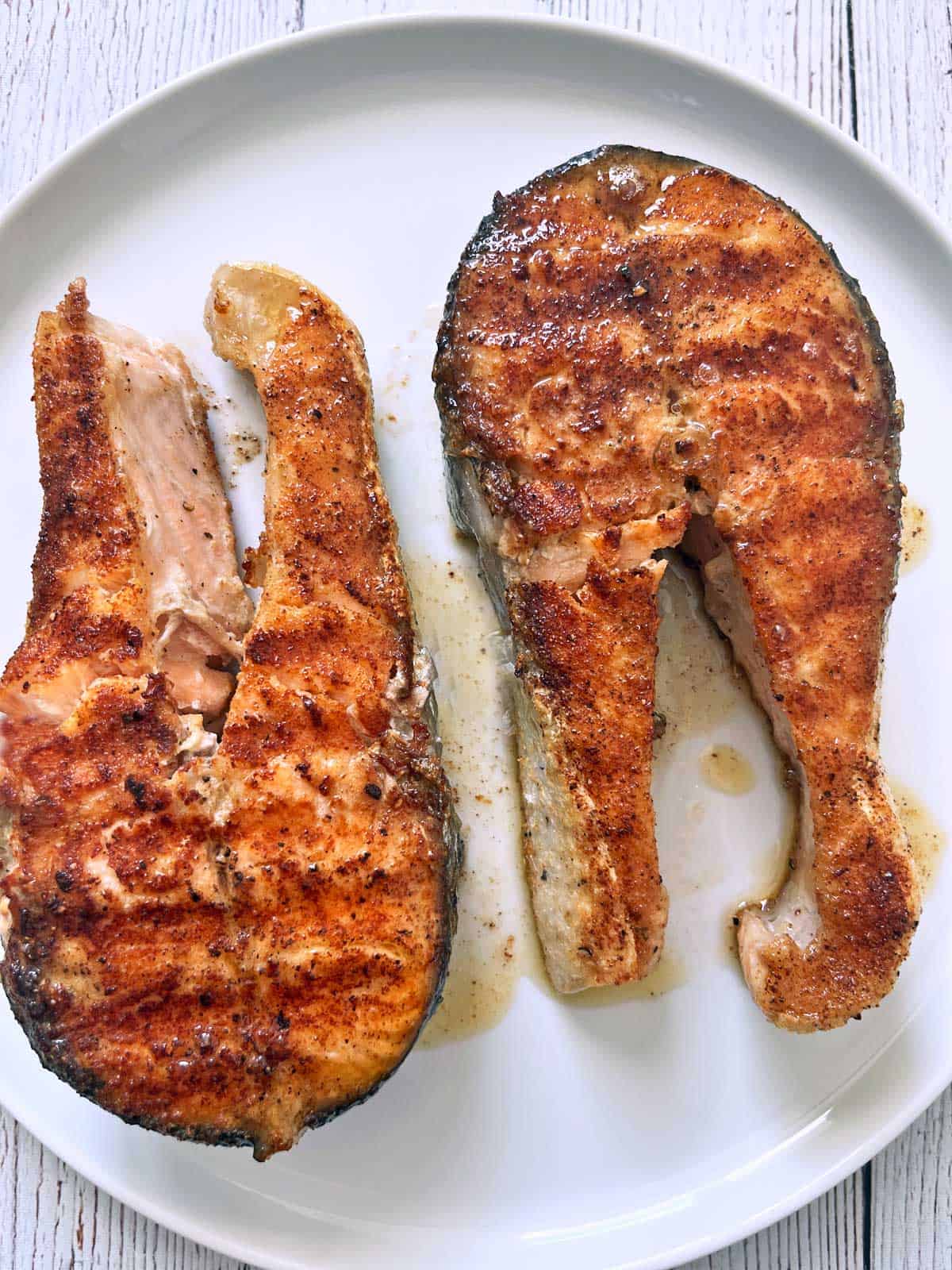Two grilled salmon steaks on a plate.
