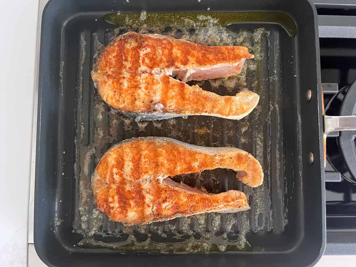 Two salmon steaks in a grill pan.