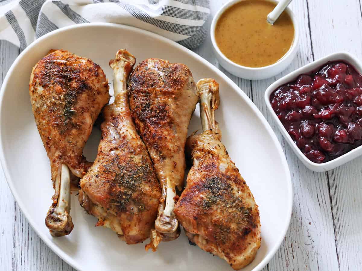 Turkey legs are served with gravy and cranberry sauce.