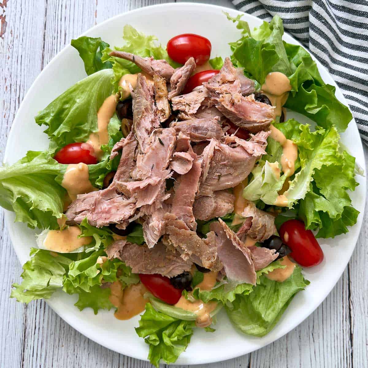 A salad made with leftover turkey, lettuce, tomatoes, olives, and a dressing.
