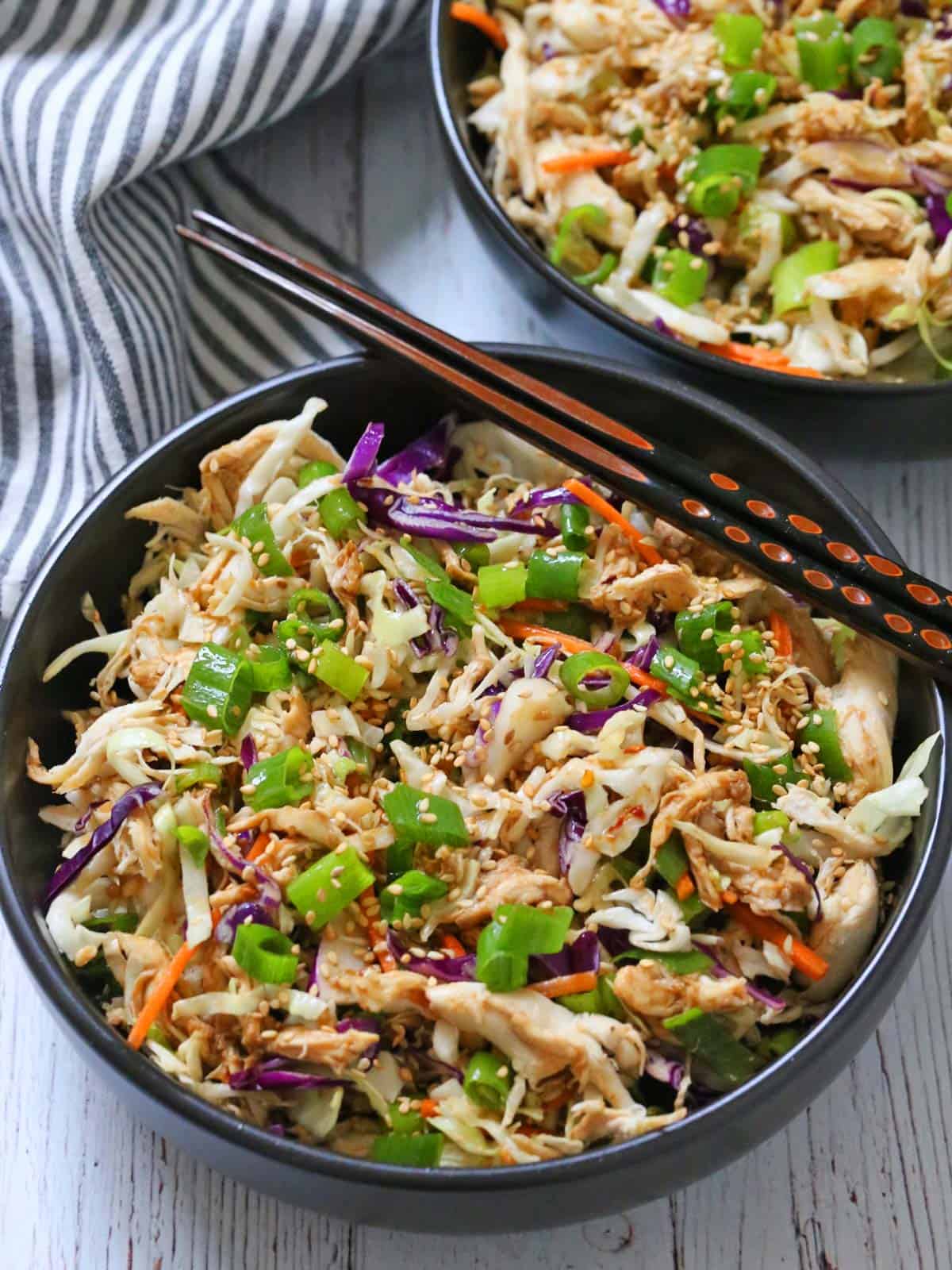 Chinese chicken salad is served in a bowl with chopsticks.