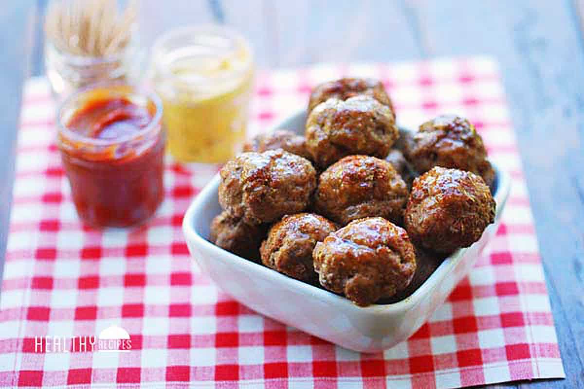 Cocktail meatballs are served with mustard and ketchup.