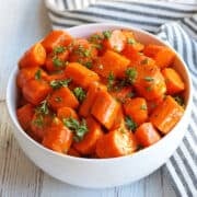 Glazed carrots are served in a white bowl.