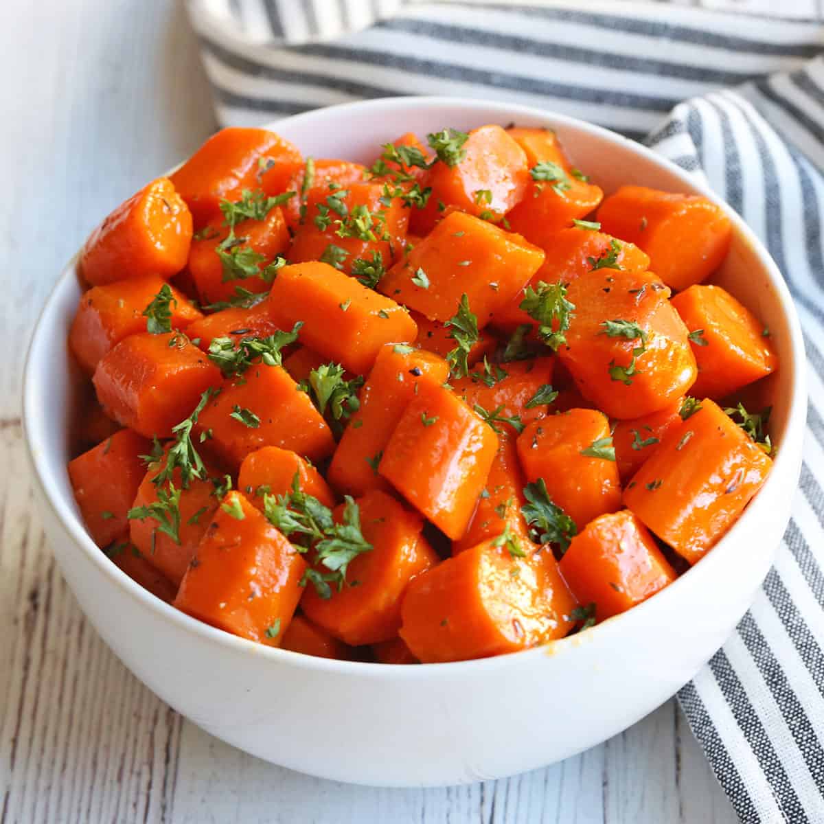 Glazed carrots are served in a white bowl.