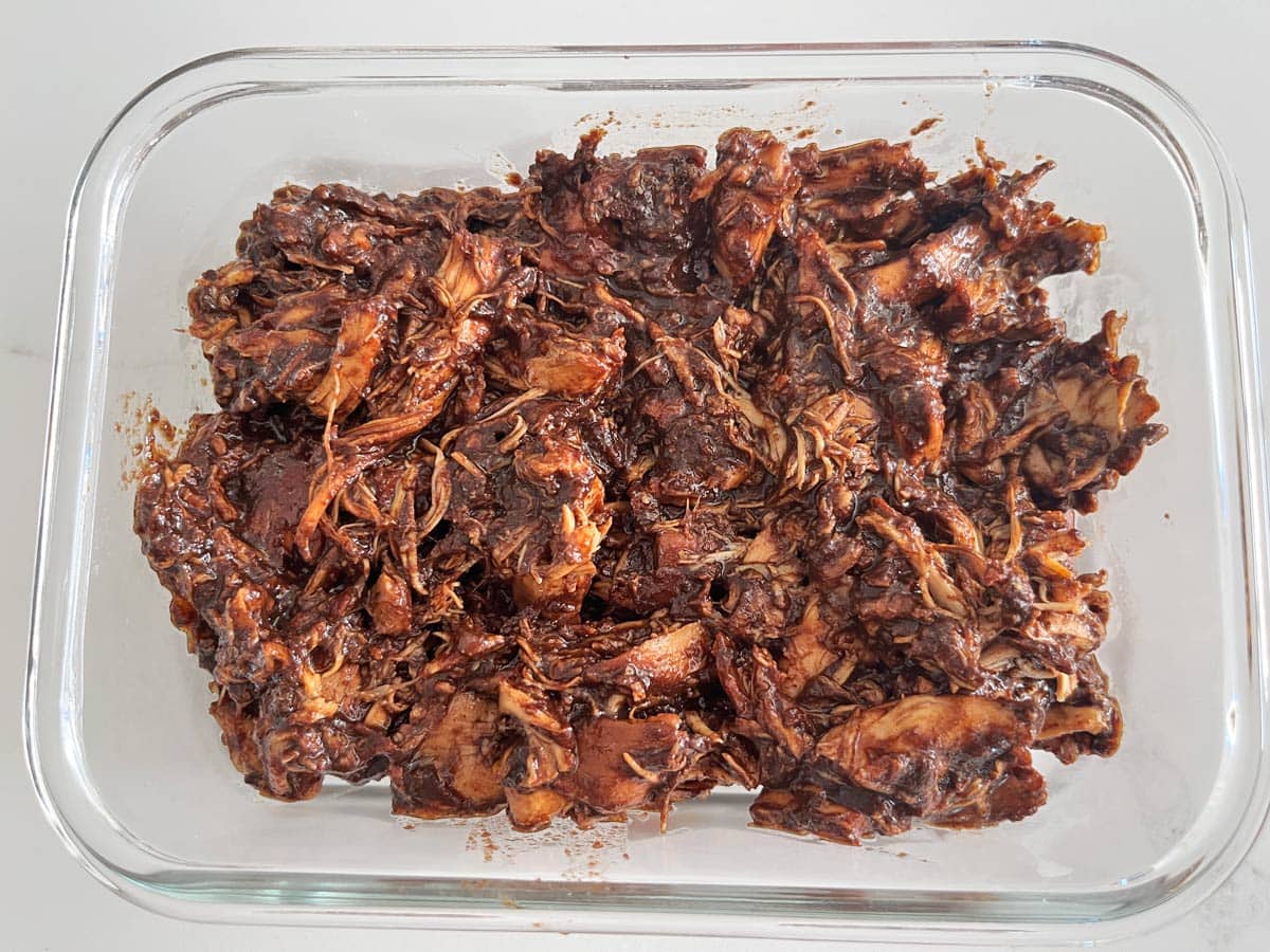 Pulled chicken leftovers are stored in a glass container.