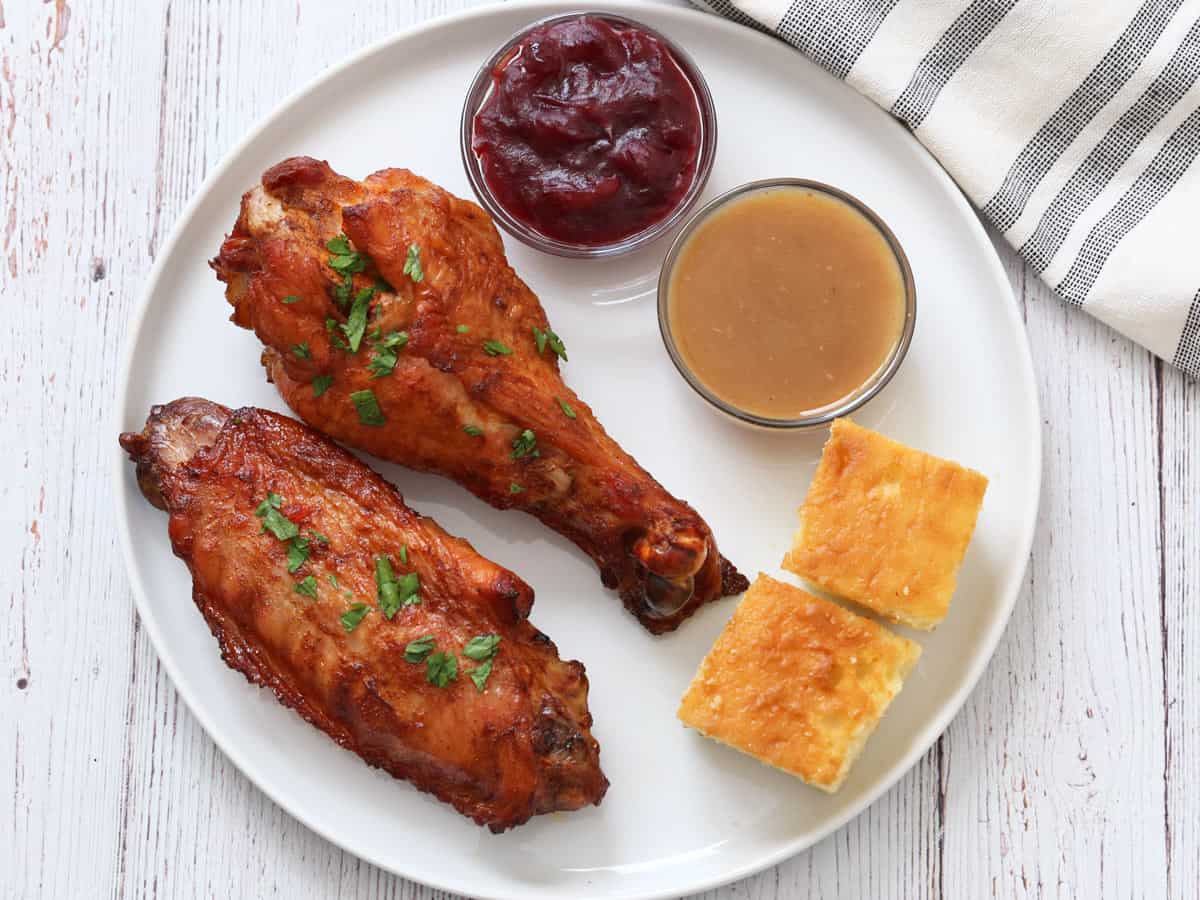Turkey wings are served for Thanksgiving with gravy, cranberry sauce, and cornbread.