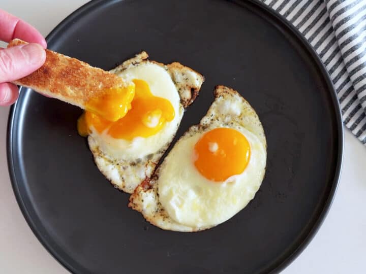Bread is dipped into a sunny-side up egg.