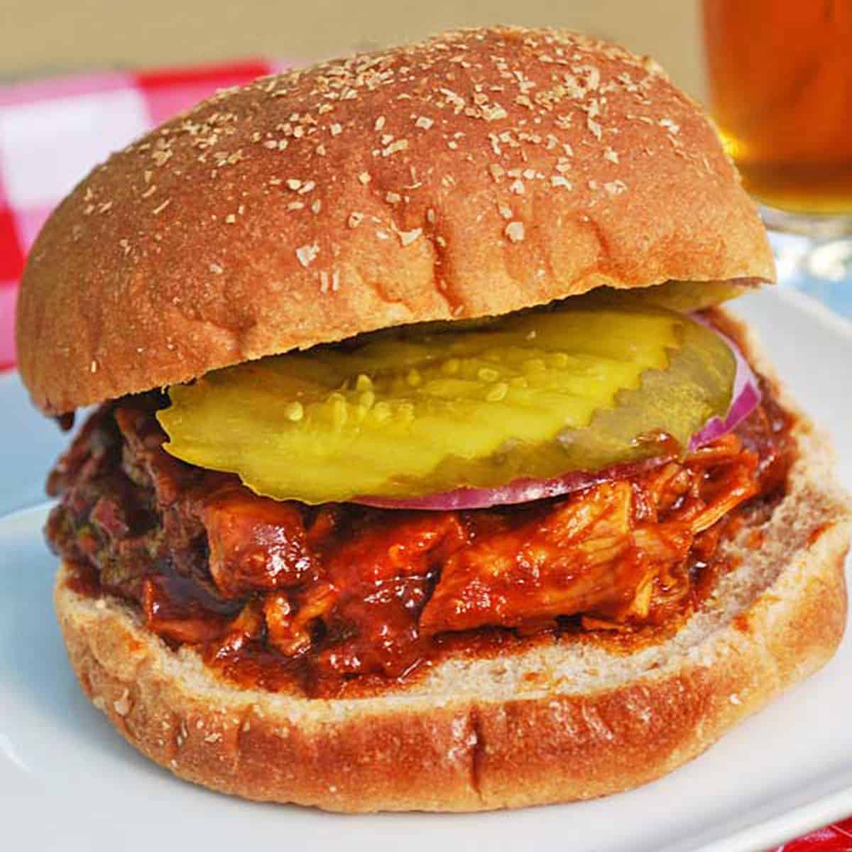 Pulled chicken is served in a bun with red onions and pickles.
