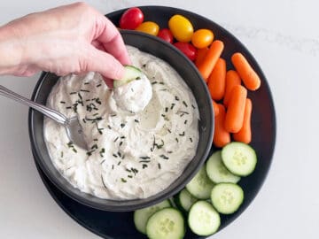 Scooping the dip with a cucumber slice.