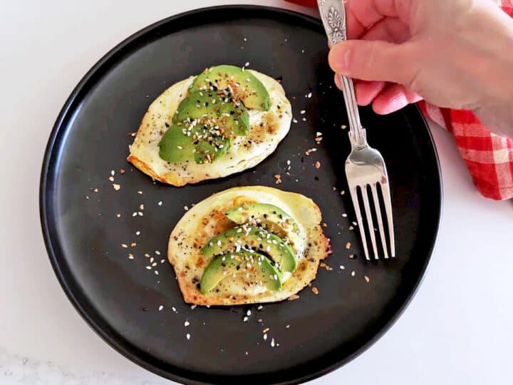 The eggs are served, topped with avocado.