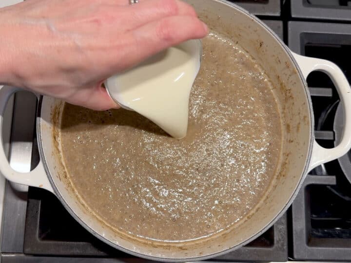 Adding heavy cream to the soup.