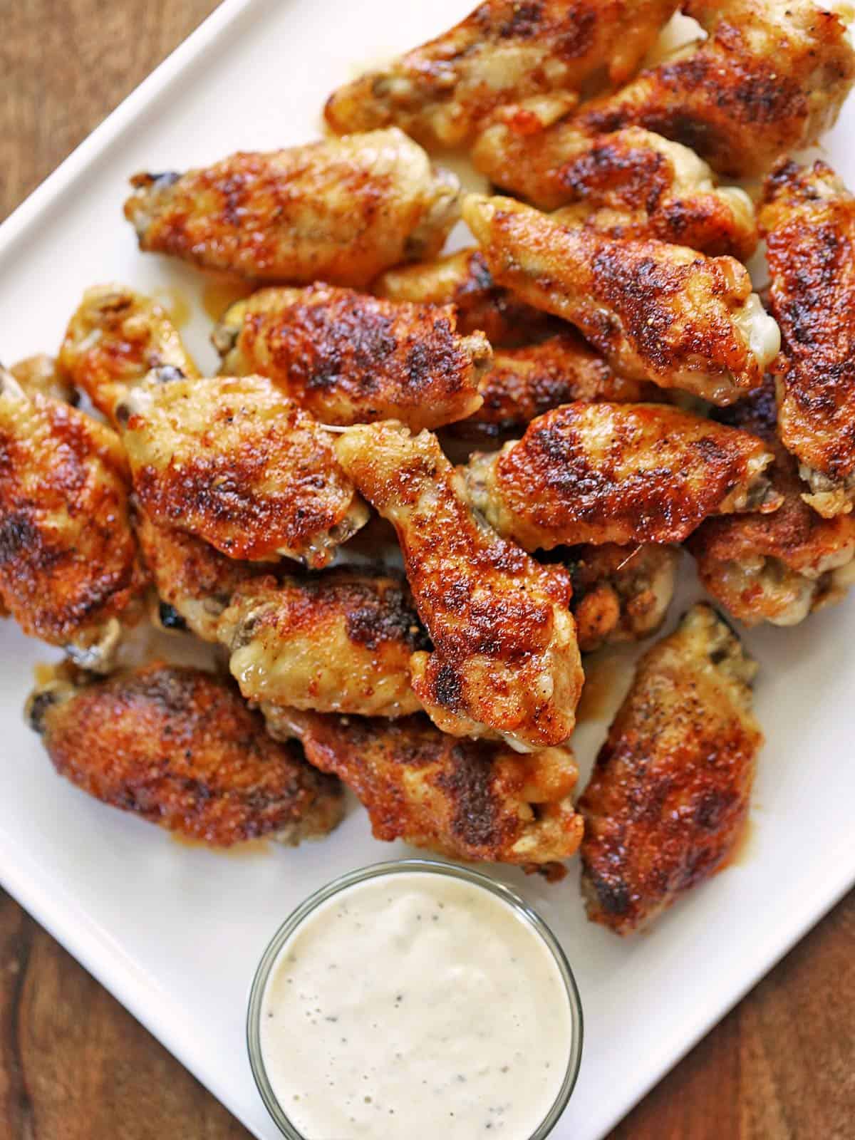 Chicken wings are served with ranch dressing for dipping.