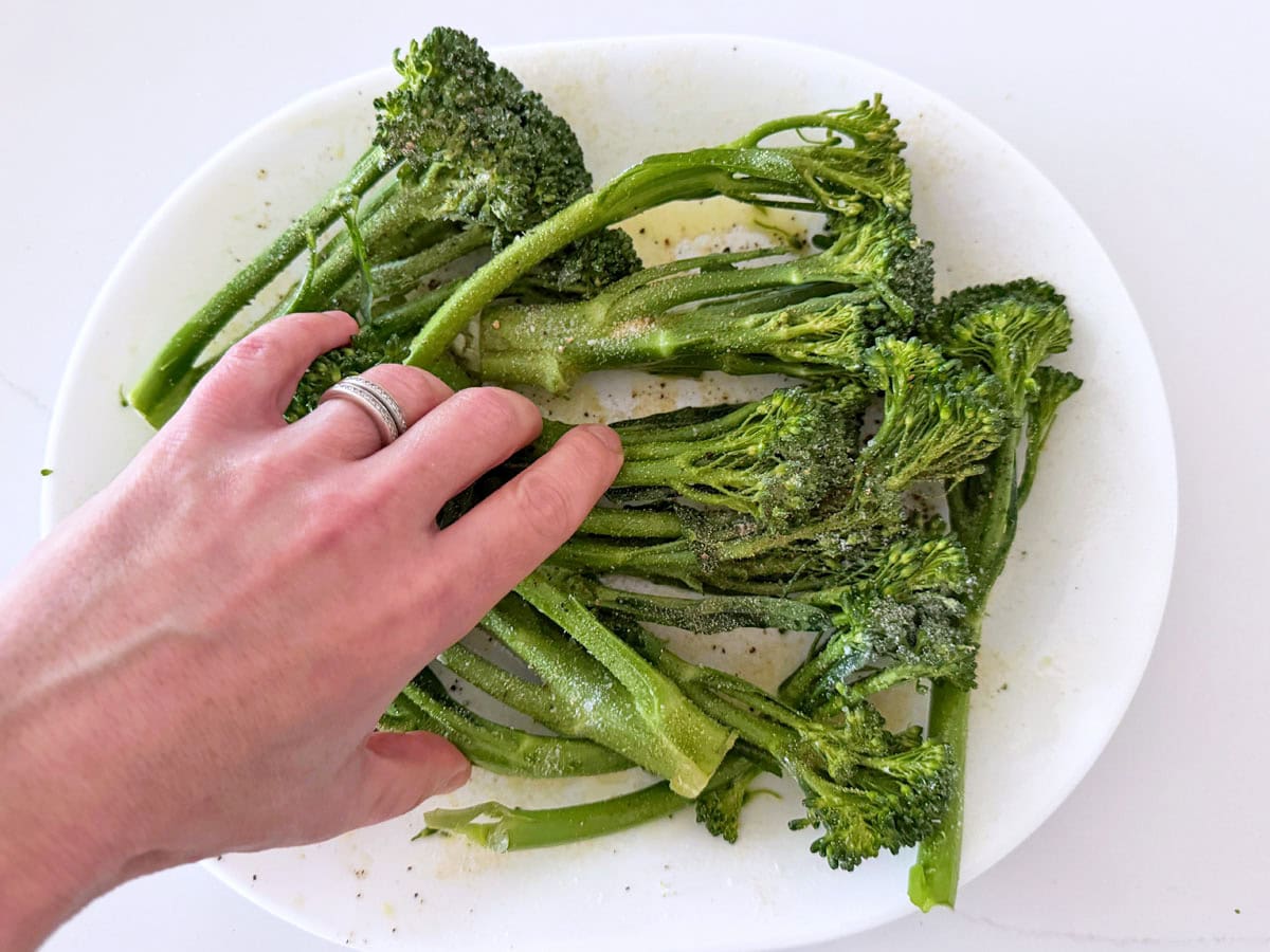 Coating the broccolini in oil and spices.