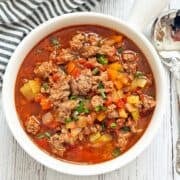 Hamburger soup is served in a white bowl.