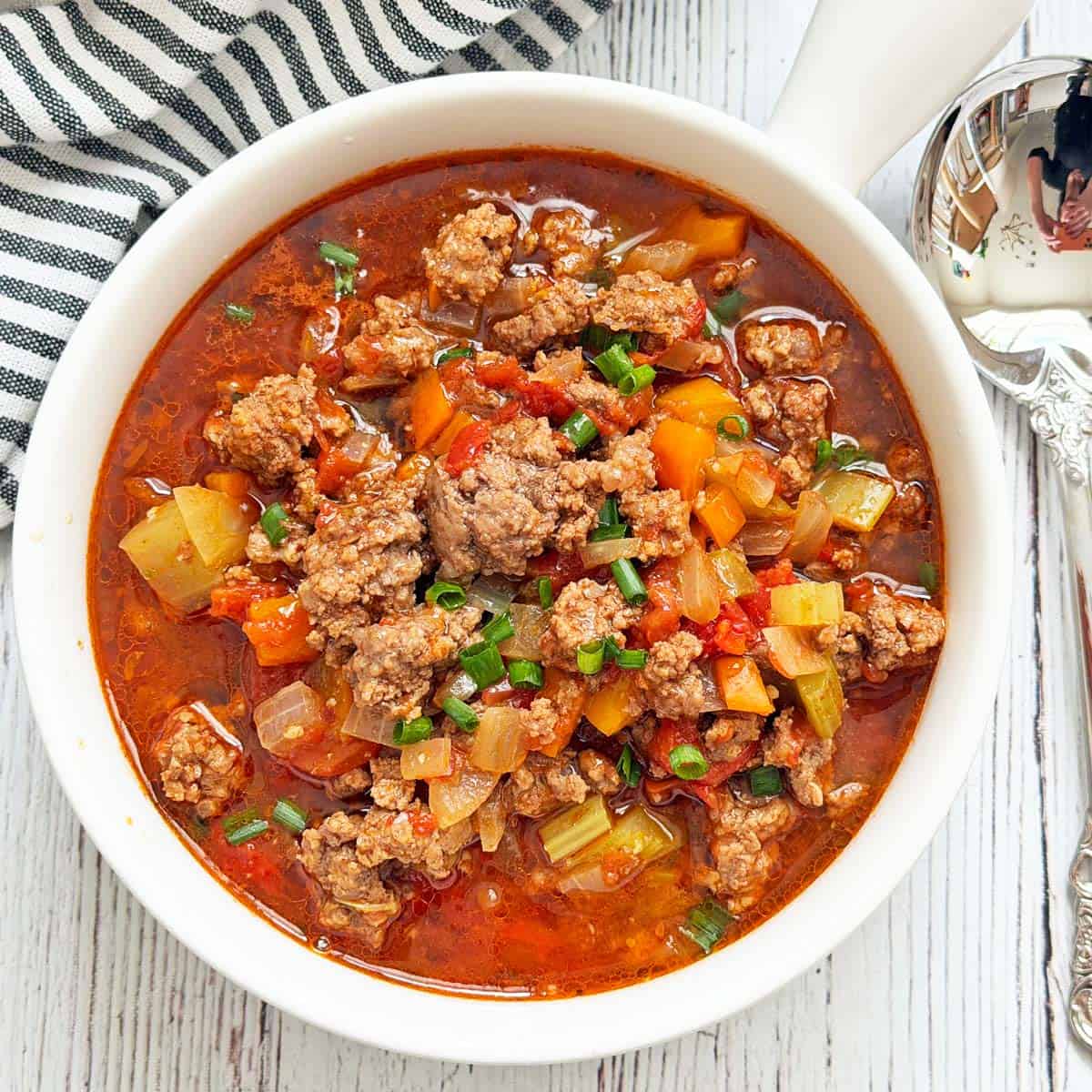Hamburger soup is served in a white bowl.