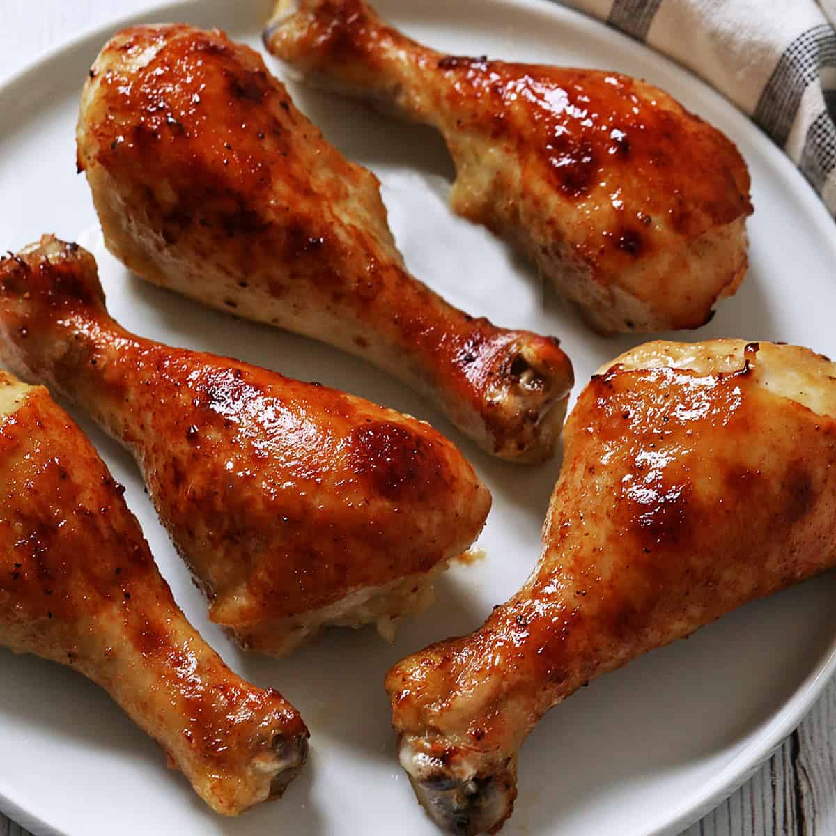 Honey garlic chicken is served on a white plate with a napkin.