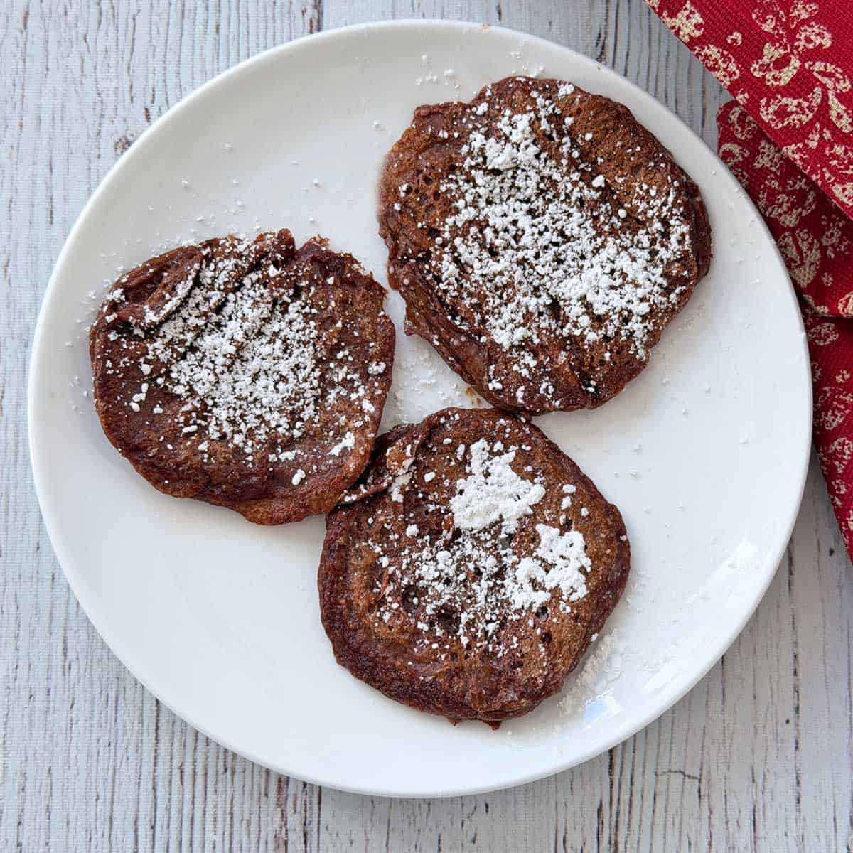 Three chocolate protein pancakes on a plate.