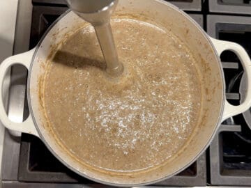 Pureeing the soup using an immersion blender.