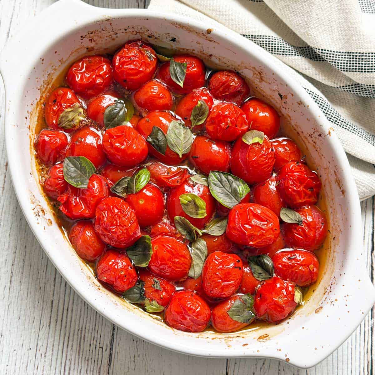 Roasted cherry tomatoes are topped with basil.