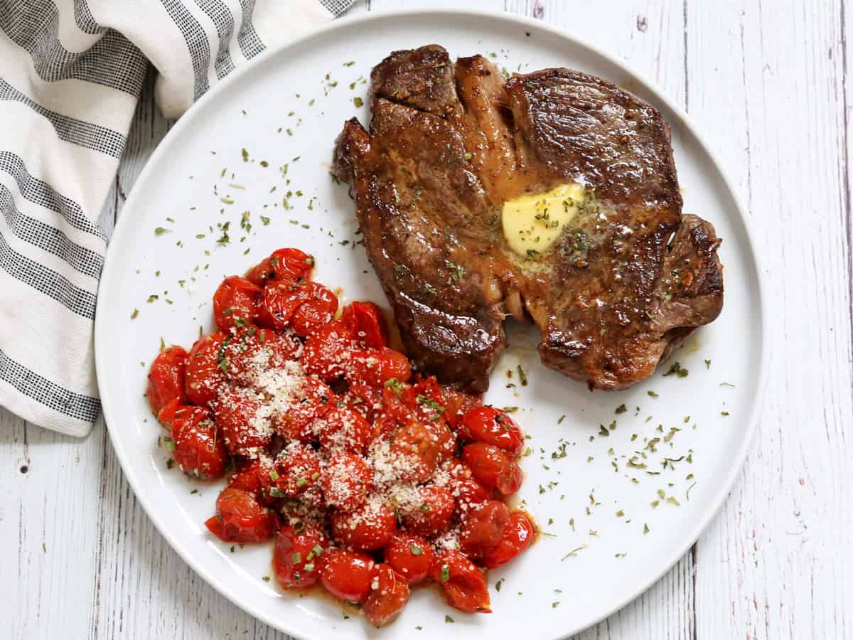 Roasted cherry tomatoes are topped with Parmesan and served with steak.